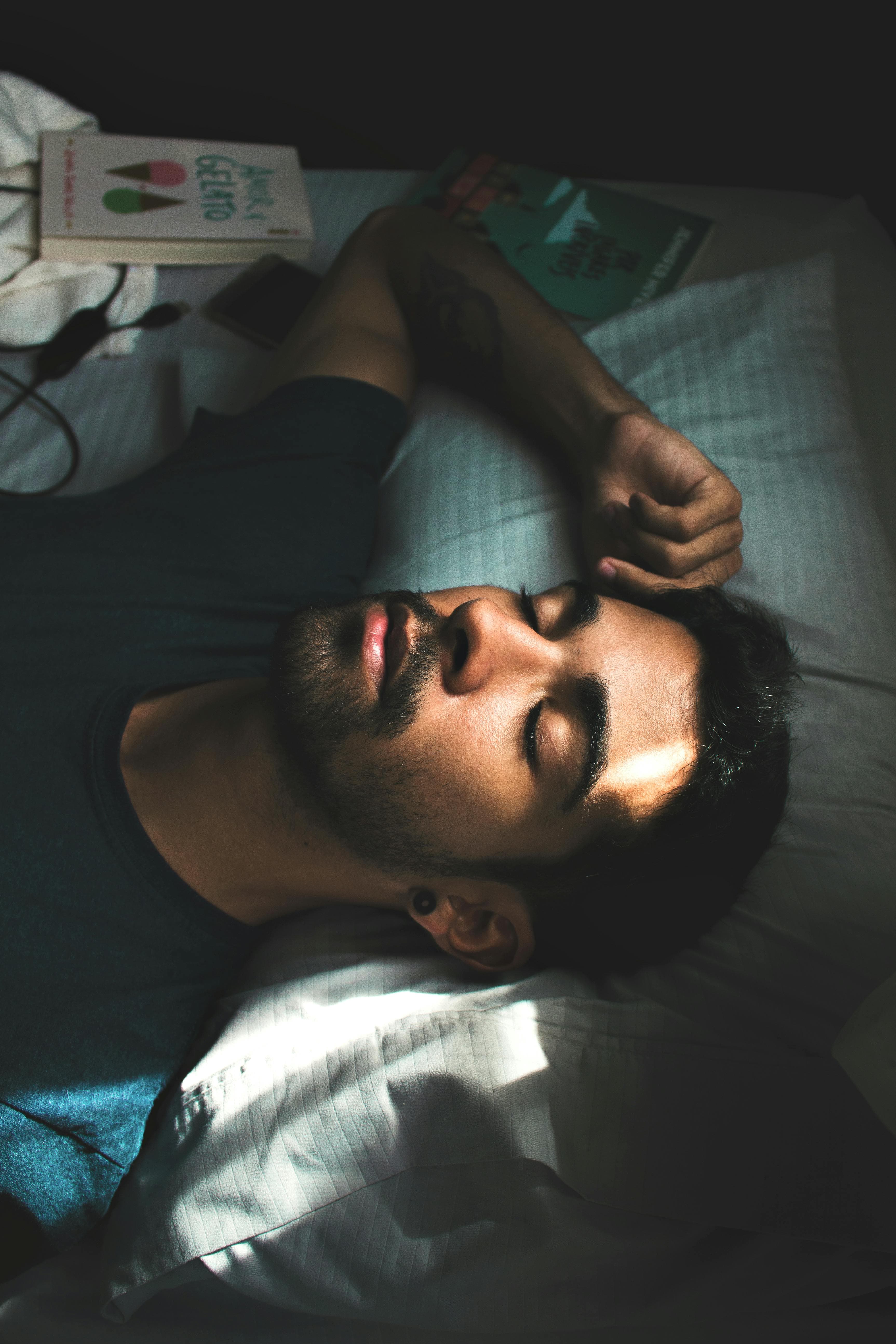 A bearded man sleeps on a white pillow with sunlight illuminating his face.
